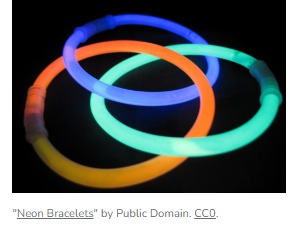 Photo of three overlapping glowing neon bracelets on a black background.